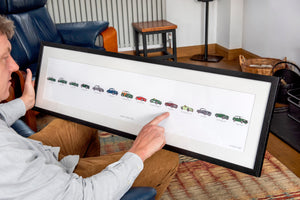 Person interacting with a framed artwork display showing a series of car illustrations in a living room.