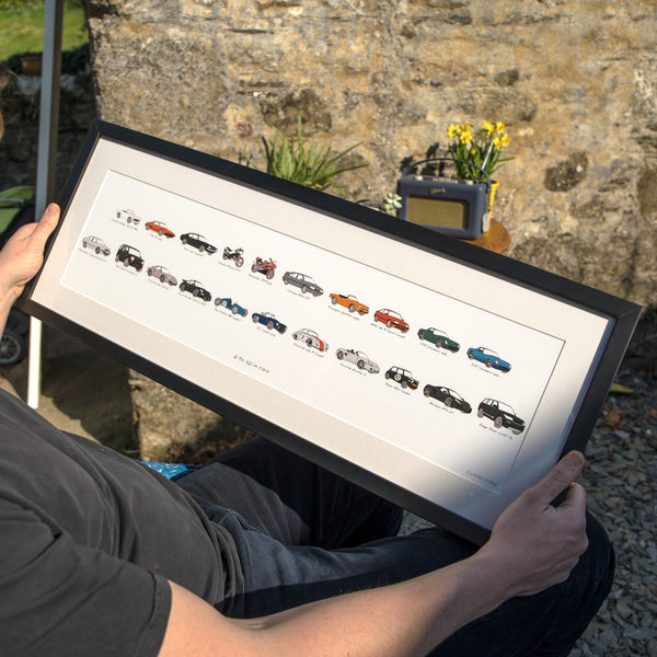 man holding his car history artwork in a frame. my life in cars. Carvolution® Your life in cars, bespoke car art, car history gift, carvolution logo, car logo, my life in cars, car gift for men, personalised car artwork, framed car artwork, car drawings, classic car drawings, framed artwork, artwork delivery, artwork lifestyle shot, life style photography, professionally framed artwork, fine art guild framers, above and beyond personalised gift, bespoke car print, framed car artwork, dry mounted prints.